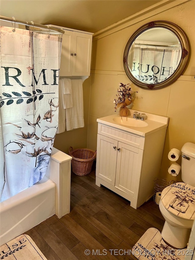 bathroom with toilet, shower / bathtub combination with curtain, wood finished floors, and vanity