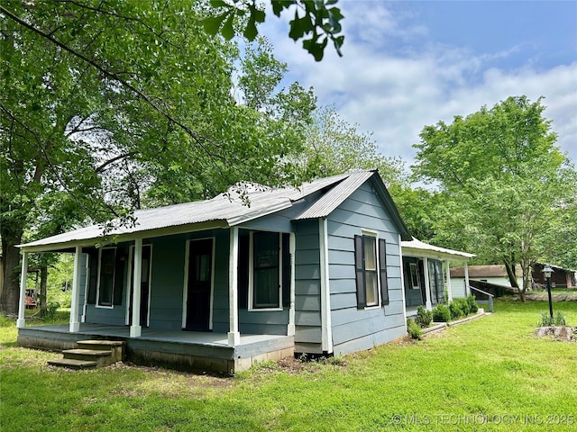 view of side of property featuring a yard, a porch, and metal roof