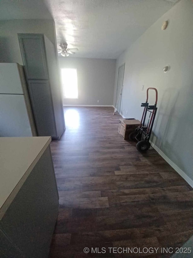hallway with dark wood-style flooring and baseboards