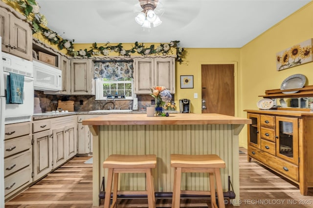 kitchen with a ceiling fan, wooden counters, a sink, white appliances, and light wood-style flooring