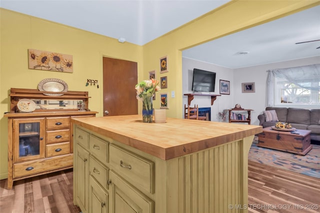 kitchen featuring cream cabinetry, open floor plan, butcher block counters, and wood finished floors