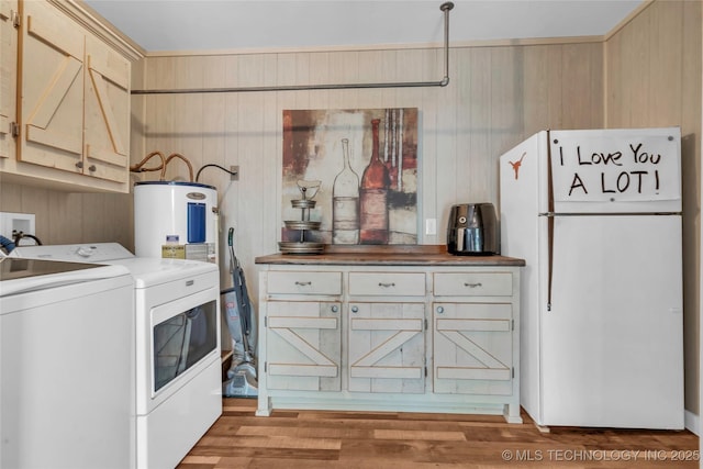 washroom featuring light wood-type flooring, washer and clothes dryer, cabinet space, and wood walls