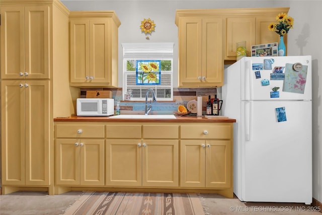 kitchen featuring decorative backsplash, butcher block counters, light brown cabinetry, white appliances, and a sink