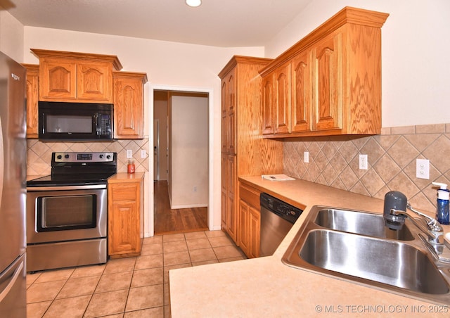 kitchen with light countertops, light tile patterned floors, a sink, appliances with stainless steel finishes, and backsplash