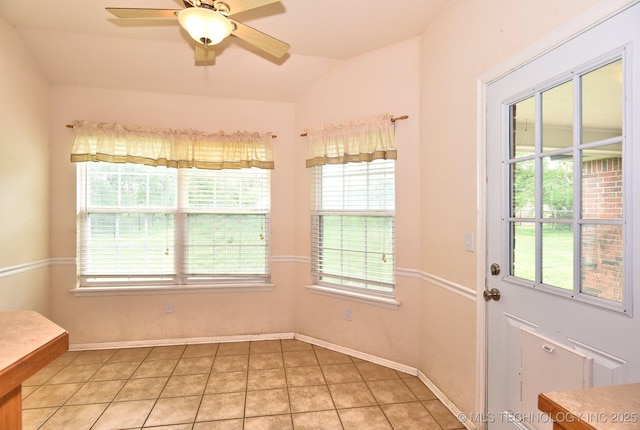interior space featuring baseboards, a ceiling fan, light tile patterned floors, and vaulted ceiling