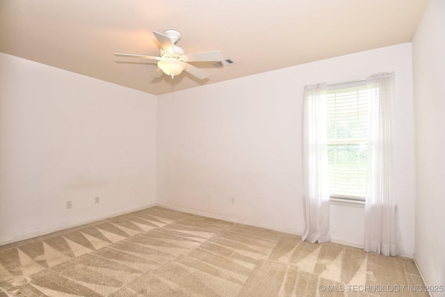 spare room featuring a ceiling fan, a healthy amount of sunlight, and light carpet