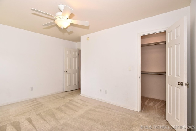 unfurnished bedroom with ceiling fan, a spacious closet, carpet, and a closet