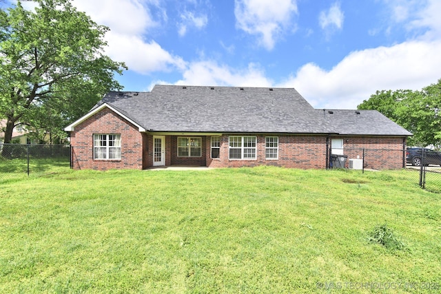 back of house with a lawn, brick siding, a fenced backyard, and roof with shingles