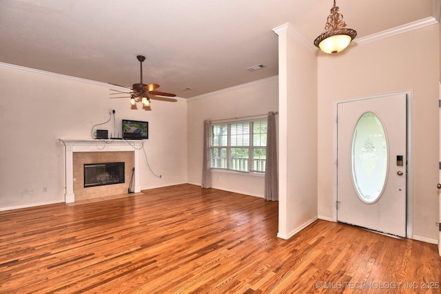 foyer entrance with crown molding, a ceiling fan, wood finished floors, and a tile fireplace