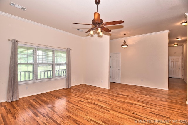 empty room featuring crown molding, visible vents, wood finished floors, baseboards, and ceiling fan