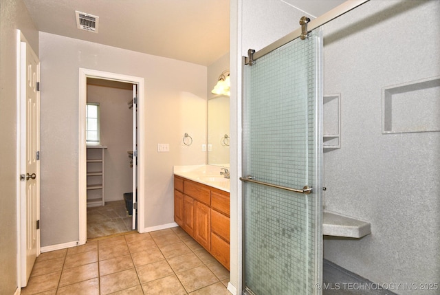 bathroom featuring visible vents, tile patterned flooring, vanity, baseboards, and a shower with door