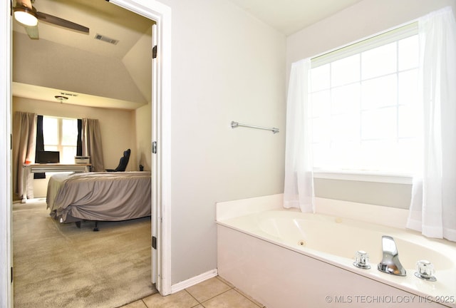 ensuite bathroom with tile patterned floors, a ceiling fan, vaulted ceiling, visible vents, and a garden tub
