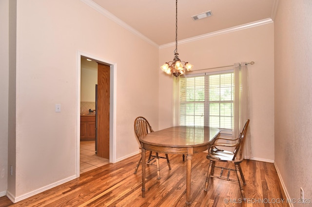 dining room featuring crown molding, a notable chandelier, baseboards, wood finished floors, and visible vents