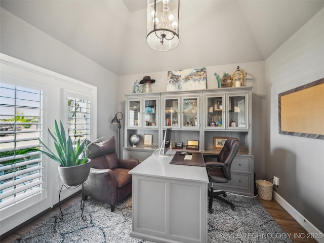 home office featuring wood finished floors, baseboards, lofted ceiling, and an inviting chandelier