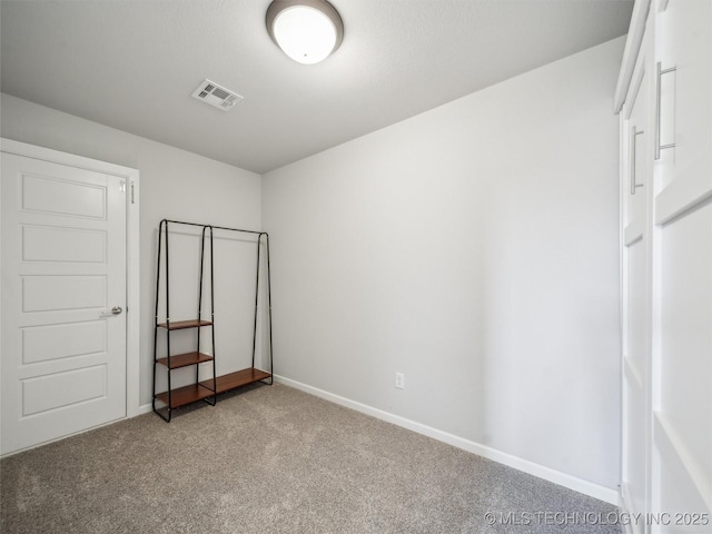 unfurnished bedroom featuring baseboards, visible vents, and carpet