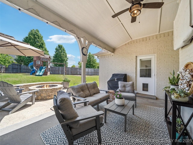 view of patio / terrace with area for grilling, ceiling fan, a fenced backyard, a playground, and an outdoor living space with a fire pit