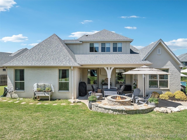 back of property with a patio area, brick siding, an outdoor fire pit, a yard, and a shingled roof