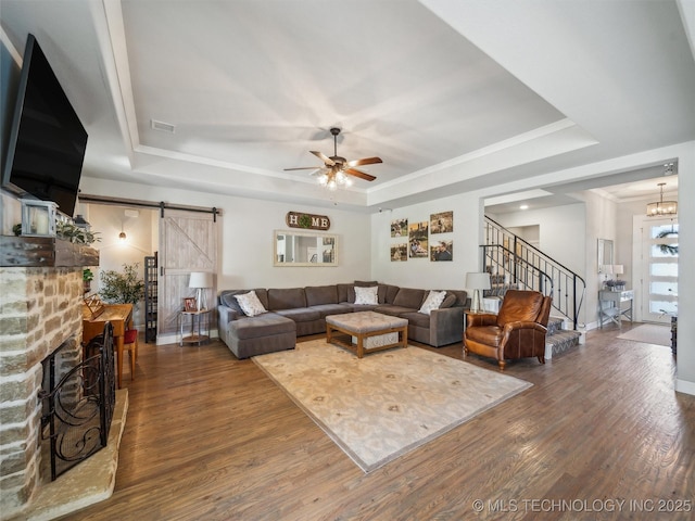 living area featuring a barn door, a raised ceiling, wood finished floors, and stairway