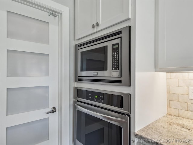 kitchen featuring light countertops, backsplash, stainless steel appliances, and white cabinetry