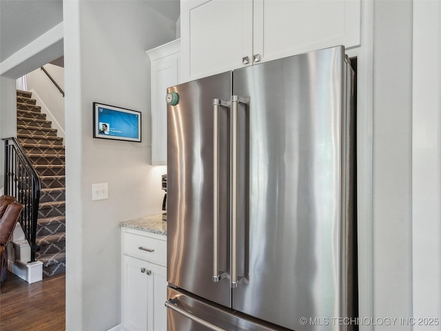 kitchen featuring white cabinets, high end fridge, light stone counters, and dark wood-type flooring