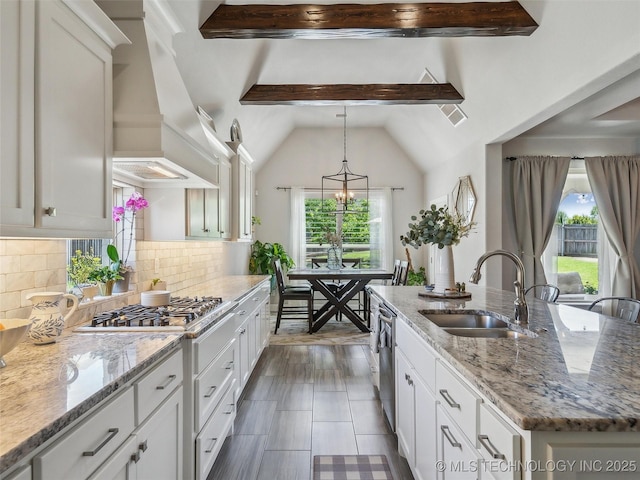 kitchen featuring stainless steel gas stovetop, a sink, a healthy amount of sunlight, and a center island with sink