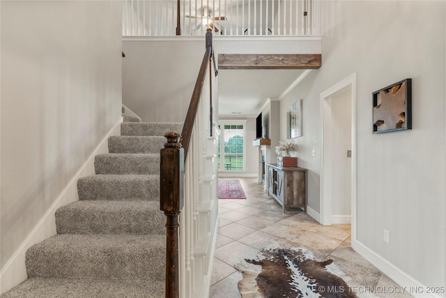 stairway with baseboards, ornamental molding, and tile patterned flooring