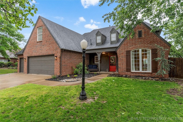 view of front of house with fence, brick siding, a garage, a porch, and a front yard