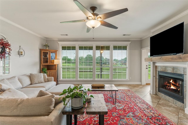 living area with visible vents, ornamental molding, ceiling fan, a tiled fireplace, and light tile patterned floors