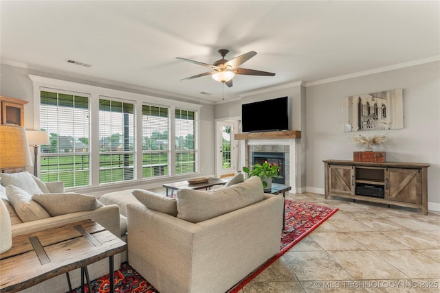 living room with crown molding, a ceiling fan, visible vents, and a tiled fireplace