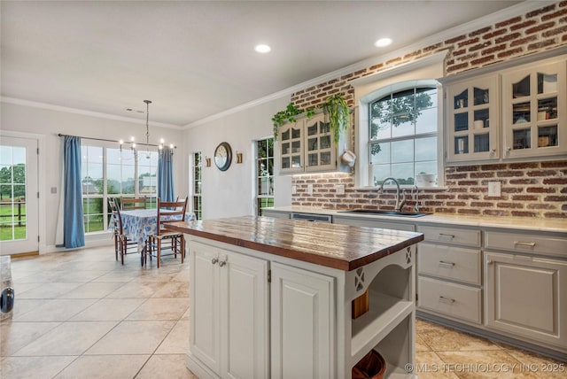 kitchen with open shelves, a sink, a chandelier, ornamental molding, and butcher block countertops