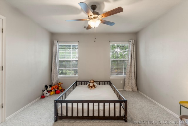 carpeted bedroom featuring baseboards, multiple windows, and ceiling fan