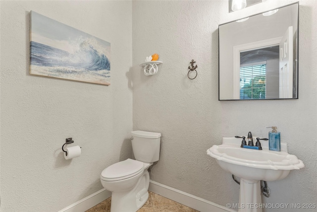 half bathroom featuring baseboards, tile patterned flooring, and toilet