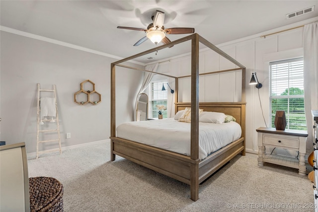 carpeted bedroom featuring visible vents, ornamental molding, baseboards, and ceiling fan