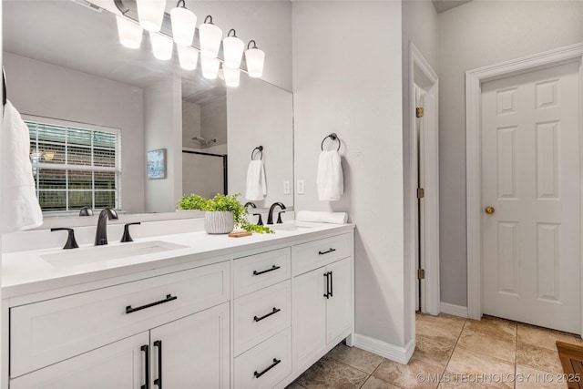 full bathroom with double vanity, baseboards, a shower stall, and a sink