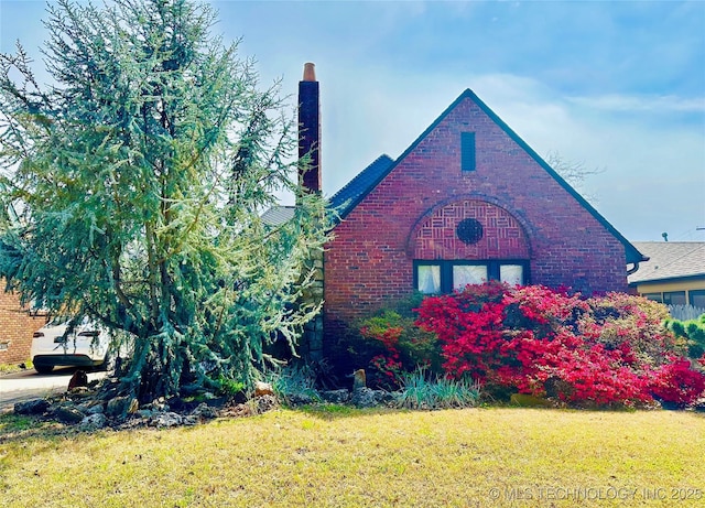 view of property exterior featuring a lawn, brick siding, and a chimney