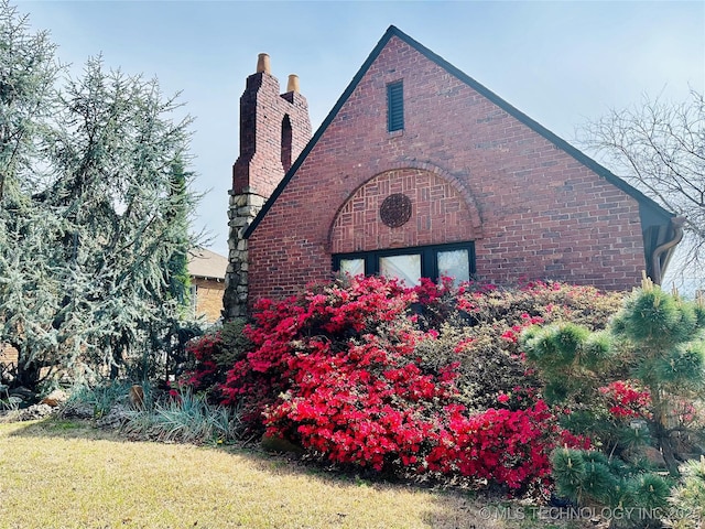 view of side of property featuring brick siding, a garage, and a chimney