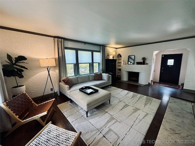 living room featuring crown molding, a textured wall, a fireplace, and wood finished floors
