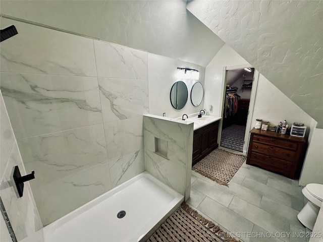 bathroom with vanity, lofted ceiling, toilet, a spacious closet, and a stall shower