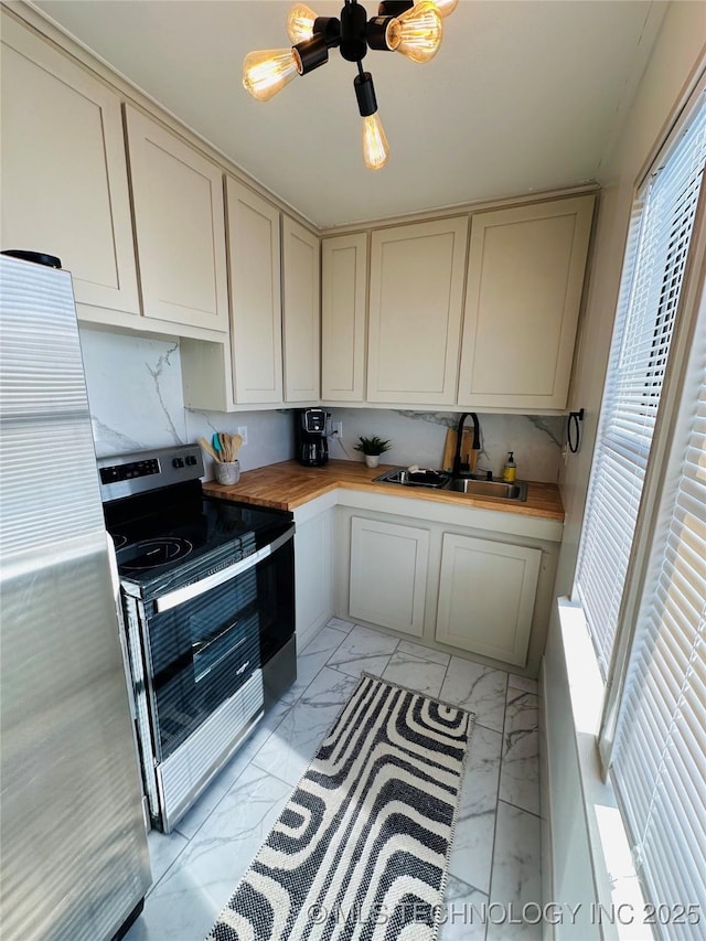 kitchen featuring butcher block countertops, appliances with stainless steel finishes, a sink, and marble finish floor