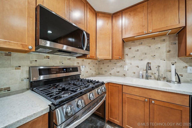 9998 E 460th Rd, Claremore, OK 74017 - kitchen featuring stainless steel appliances, a sink, tasteful backsplash, brown cabinetry, and light stone counters