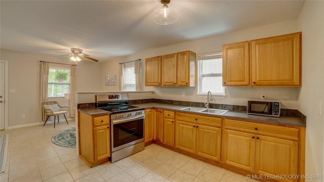 kitchen with a peninsula, dark countertops, a sink, and stainless steel range with electric stovetop