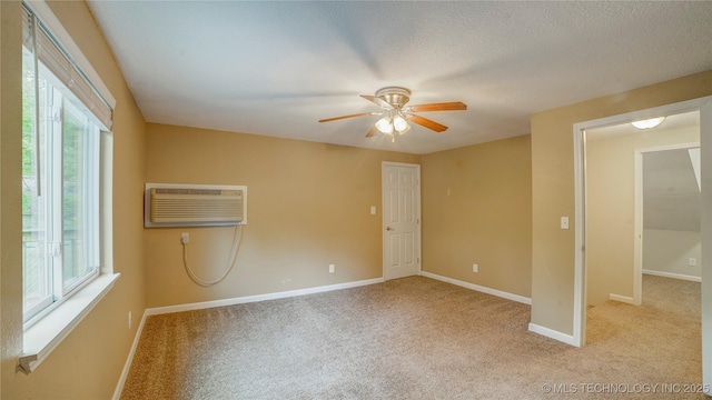 empty room featuring light colored carpet, ceiling fan, a wall mounted AC, and a wealth of natural light