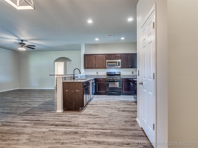 kitchen with dark brown cabinetry, light wood-style flooring, stainless steel microwave, and black range with gas stovetop
