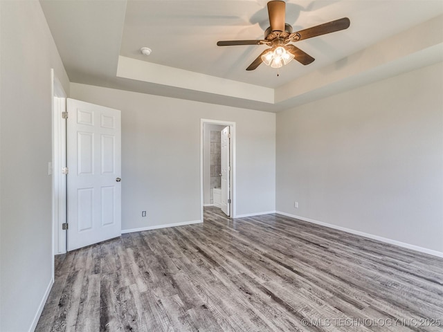 spare room with a raised ceiling, baseboards, a ceiling fan, and wood finished floors