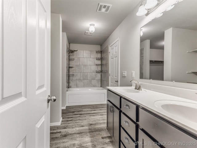 full bath featuring double vanity, wood finished floors, shower / tub combination, a sink, and visible vents