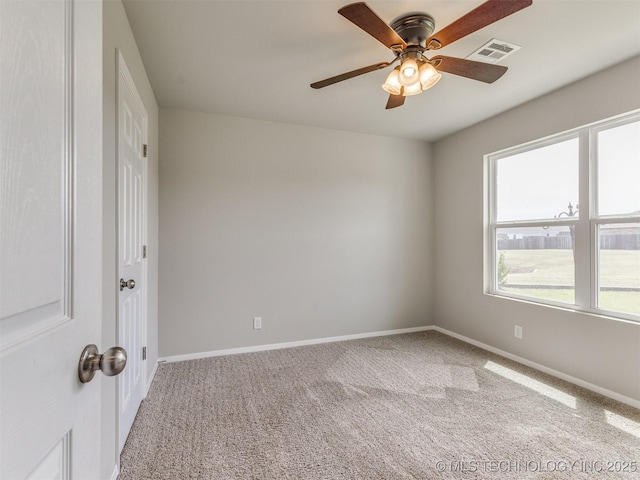carpeted empty room featuring a wealth of natural light, baseboards, a ceiling fan, and visible vents
