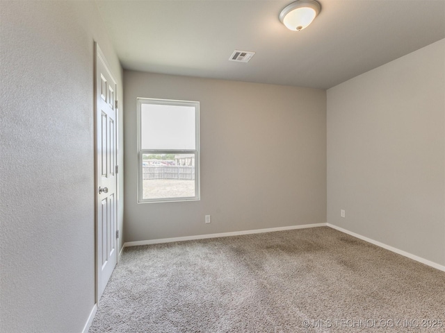 unfurnished room featuring carpet, visible vents, and baseboards