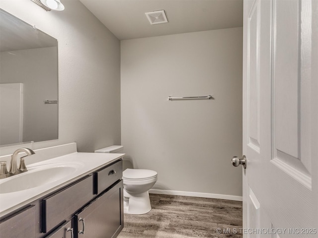 bathroom with toilet, baseboards, visible vents, vanity, and wood finished floors