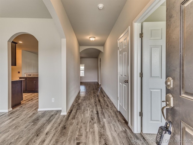 corridor featuring baseboards and wood finished floors