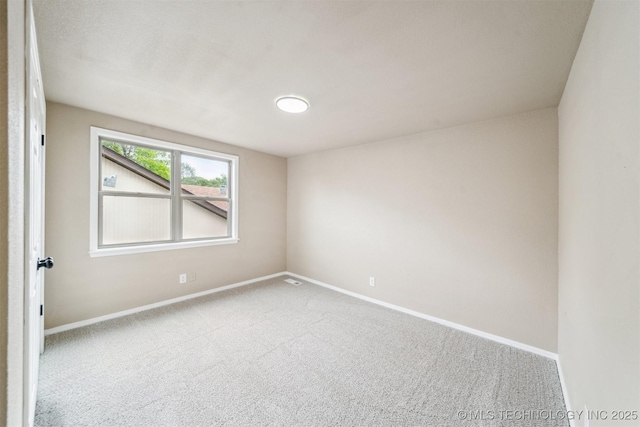 carpeted empty room featuring baseboards